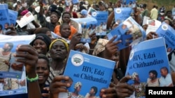 FILE - Parents, guardians, friends and relatives sing traditional songs and carry HIV/AIDS prevention posters during a boys initiation into manhood ceremony in Njoloma village, Malawi.