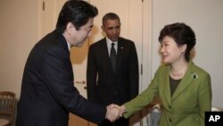지난 3월 네덜란드 헤이그에서 열린 미-한-일 3국 정상회담에 앞서 박근혜 한국 대통령(왼쪽)과 아베 신조 일본 총리가 악수하고 있다. 바락 오바마 미국 대통령(가운데)이 이를 지켜보고 있다. (자료사진)