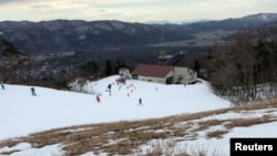 Grass comes up through the snow as people enjoy skiing at a ski resort in Hakuba village, central Japan on February 22, 2020. (Reuters/Jack Tarrant)