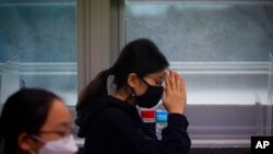 FILE - A student wearing a face mask prays before the start of the annual college entrance examination amid the coronavirus pandemic in Seoul, South Korea, Dec. 3, 2020.