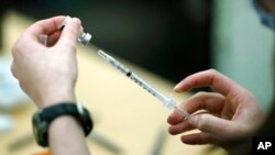 FILE - A worker fills a syringe with the Pfizer COVID-19 vaccine at the Yakima Valley Farm Workers Clinic in Toppenish, Wash., March 25, 2021. 