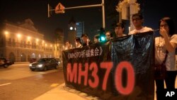 People hold a banner and candles during a candlelight vigil for passengers aboard a missing Malaysia Airlines plane in Kuala Lumpur, Malaysia, Monday, March 10, 2014.