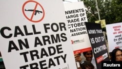 FILE - Activists campaigning for a global arms trade treaty hold placards during a protest in New Delhi, India.