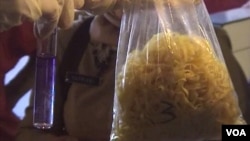 Petugas BBPOM Bandung menunjukkan sampel mie yang diperoleh dari pasar Tradisional Ancol di Bandung. Setelah diuji, cairan kimia dalam tabung berubah warna menjadi ungu (Foto: VOA/Teja Wulan)