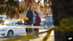 Yia Lee watches police investigate her neighbor's house on Lamona Ave. where a shooting took place at a house party which involved multiple fatalities and injuries in Fresno, Calif., Monday, Nov. 18, 2019. (AP Photo/Gary Kazanjian)