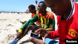 ARSIP – Seorang pria Somalia bersilancar di internet dengan telepon pintarnya di garis pantai Samudra Hindia di ibukota Somalia, Mogadishu, 10 Januari 2014 (foto: REUTERS/Feisal Omar)