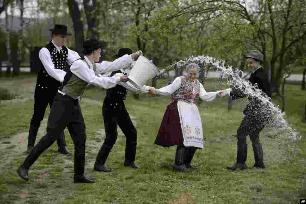 Young men dressed in traditional Paloc folk costumes pour water from a bucket on a young woman performing a folk tradition, the Easter sprinkling, in Kazar, some 100 kilometers northeast of Budapest, Hungary, Good Friday, April 18, 2014.&nbsp;