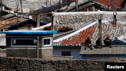 지난 5월 중국 접경도시 장백에서 압록강 너머로 바라본 북한 혜산. 군인으로 보이는 남성들이 초소 지붕 위에 앉아있다.