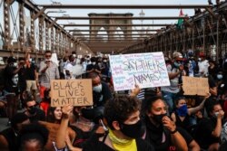 Protesters take a knee before continuing their march on the Brooklyn Bridge after attending a memorial service for George Floyd on June 4, 2020, in the Brooklyn borough of New York.