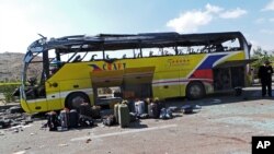 An Egyptian policeman stands guard in front of a damaged bus after a deadly explosion Sunday near the Egyptian border crossing with Israel in Taba, Egypt, Feb. 17, 2014.