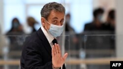 Former French president Nicolas Sarkozy waves as he leaves the court room during a break of his trial for attempted bribery of a judge, in Paris on November 23, 2020