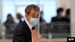 L'ancien président français Nicolas Sarkozy salue en quittant la salle d'audience lors d'une pause de son procès pour tentative de corruption d'un juge, à Paris le 23 novembre 2020.