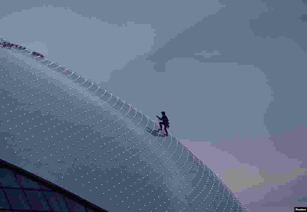 A workman climbs up the roof of the Bolshoy Ice Dome as preparations continue at the Olympic Park for the Sochi 2014 Winter Olympics in Russia. The Bolshoy Ice Dome will host the Olympic ice hockey competition.