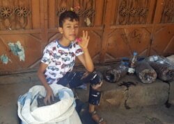 A boy holds up a pink mature locust. (N. Shaker/VOA)