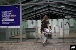 A woman enters at the Museum of Broken Relationships in Pristina, Kosovo, May 3, 2018 Toy dolls, a memory jar, a magnifying glass, book notes, a blouse, scissors, pens and pencils, a dust cleaner, a condom — a growing collection of items, each a memento o