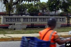 FILE - A motorcyclist rides past the General Motors' plant in Valencia, Venezuela, April 20, 2017.