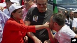 A supporter kisses the hand of Dilma Rousseff, presidential candidate of the ruling Workers Party, as Belo Horizonte mayor Marcio Lacerda looks on, during a campaign rally in Belo Horizonte, Brazil, 30 Oct 2010