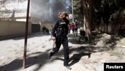 A fighter from the Islamist Syrian rebel group Jabhat al-Nusra reacts to his picture being taken as their base is shelled in Raqqa province, eastern Syria, Mar.14, 2013. 
