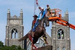 FILE - Crews attach straps to the statue of Confederate General J.E.B. Stuart on Monument in Richmond, Va., July 7, 2020.