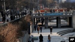 People wearing face masks walk during a lunch break at Cheonggye stream in downtown Seoul, South Korea, Jan. 4, 2021.