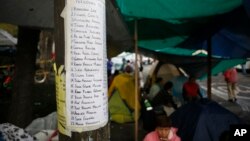 A list of missing persons is posted outside a quake-collapsed seven-story building in Mexico City's Roma Norte neighborhood, Sept. 22, 2017. Mexican officials promise to keep searching for survivors as rescue operations stretch into a fourth day.