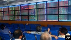 Investors and brokers watch prices at the Asia Commercial Bank (ACB) Stock Exchange in Hanoi, Vietnam.