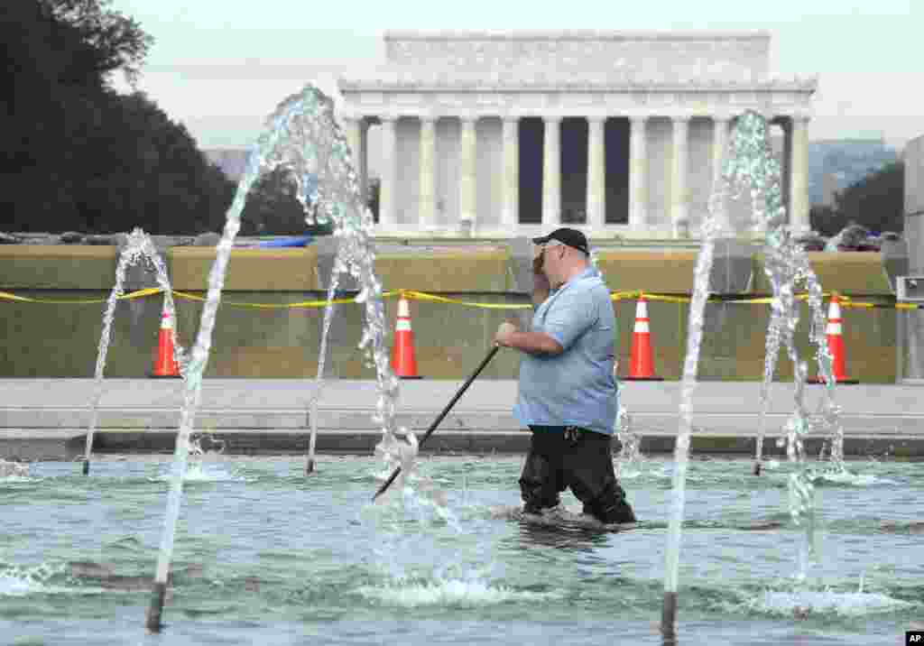 Para pekerja membersihkan kolam air mancur di Tugu Peringatan Perang Dunia II di Washington, D.C. (17/10). (AP/Susan Walsh)