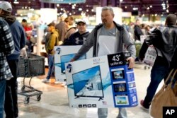 Black Friday shoppers carry their purchases at the Nebraska Furniture Mart store in Omaha, Neb., Nov. 23, 2018.
