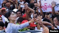 Burma's pro-democracy leader Aung San Suu Kyi touches the hands of her supporters as she arrives to attend the opening ceremony of her National League for Democracy (NLD) party's branch office in Yangon, May 23, 2012. 