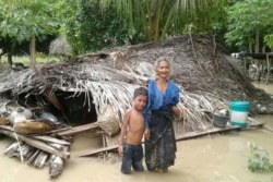 Seorang nenek dan cucunya berdiri depan rumah mereka yang rusak akibat banjir bandang di Desa Haitimuk di Flores Timur pada 4 April 2021. (Foto: AFP/Joy Christian)