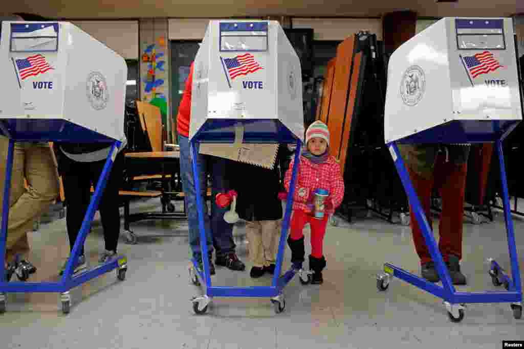 Myla Gibson, 3, waits as her father Ken Gibson fills out a ballot for the U.S presidential election at the James Weldon Johnson school in the East Harlem neighbourhood of Manhattan, New York City.
