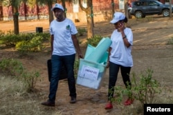 Polling staff carry a ballot box before counting at a polling center in Kigali, Rwanda, Aug. 4, 2017.