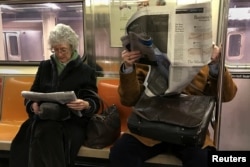 People ride the subway as they read newspapers as the train pulls into the Times Square in Manhattan, New York, Feb. 17, 2017.