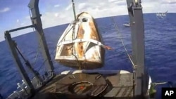 In this March 8, 2019 file image taken from video made available by NASA, the SpaceX Crew Dragon capsule is hoisted onto a ship in the Atlantic Ocean off the Florida coast after it returned from a mission to the International Space Station.