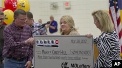 Mark (L) and Cindy (C) Hill are presented a check by a Missouri Lottery official during the announcement of Powerball winners in Dearborn, Missouri, November 30, 2012.