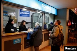 Gustavo Manfredi (R) lines up outside a postal office to register as a marijuana home grower, in Montevideo, Uruguay, Aug. 27, 2014.