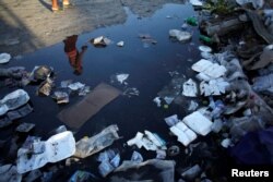 A woman is reflected in a puddle on a street in Port-au-Prince, Haiti, Aug. 17, 2016.