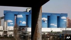 FILE - A commercial plant painted with scenes of clouds and blue skies is seen amid a residential area of Beijing, China.