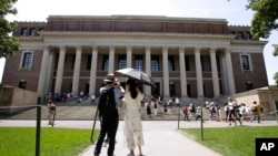 FILE - In this July 16, 2019, file photo, people stop to record images of Widener Library on the campus of Harvard University in Cambridge, Mass. 