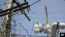 In this Oct. 19, 2017, photo, a brigade from the Electric Power Authority repairs distribution lines damaged by Hurricane Maria in the Cantera community of San Juan, Puerto Rico.