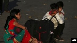 A migrant worker carries a child on his shoulders as his family waits for transportation to their village in New Delhi, India, March 28, 2020.