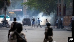 FILE - People cross a street after the police fired tear gas during a nationwide strike demanding the resignation of Haitian President Jovenel Moise, in Port-au-Prince, Haiti, Feb. 2, 2021. The government said Sunday that it had foiled a coup attempt. 