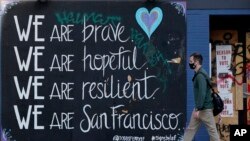 A man in a face mask walks past a sign during the coronavirus outbreak in San Francisco, Thursday, Nov. 12, 2020. (AP Photo/Jeff Chiu)