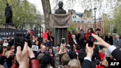 Ilustrasi. Orang-orang berpose untuk berfoto dengan patung juru kampanye hak perempuan Millicent Fawcett oleh seniman Inggris Gillian Wearing setelah diresmikan di Parliament Square di London pada 24 April 2018. (Foto; AFP)