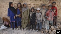 Afghan children pose for the camera, pausing during their work to sift the usable residue from the ashes of coal used at a brick factory during the cold days of a harsh winter in Kabul, Afghanistan. Thousands of Afghan children work to make money to suppo