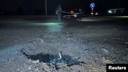 러시아 무인항공기(드론) 공격 이후 생긴 우크라이나 하르키우의 구덩이 옆에서 지난 26일 경찰관이 활동하고 있다. (자료사진)