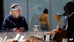 Seorang warga London dengan mengenakan pelindung wajah berbelanja di sebuah toko roti (foto: dok). 