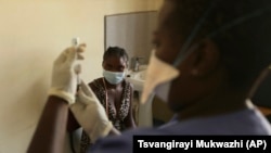 A young woman prepares to get vaccinated against COVID-19 at a health center in Harare, Zimbabwe on Friday, Sept, 24, 2021. (AP Photo/Tsvangirayi Mukwazhi)