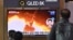 People watch a television screen showing a news broadcast with file footage of a North Korean missile test, at a railway station in Seoul on Jan. 25, 2022.