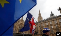 Anti-Brexit demonstrators hold up their flags opposite the Houses of Parliament in London, April 3, 2019.